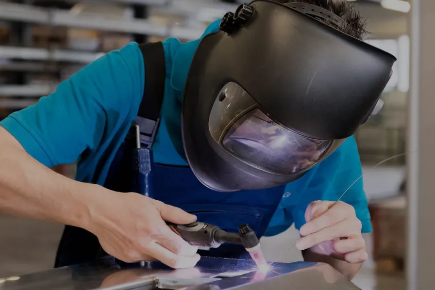 A worker in a protective helmet and goggles, working with pellet burner equipment, symbolizing the optimization of IoT infrastructure for OXI TRADE's alternative energy.
